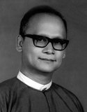 Dr. Maung Maung served in a legal capacity in General Ne Win's caretaker government from 1958–1960. Following Ne Win's 1962 military coup, Maung Maung became Chief Justice and, although a civilian, was a prominent member of the central committee of the BSPP. He played a large part in shaping the 1974 constitution and subsequent changes to the judicial system.<br/><br/>

On 19 August 1988, amidst a series of large-scale demonstrations, the People's Assembly declared Maung Maung President and Chairman of the BSPP. Anti-government demonstrations continued and widespread disruptions resulted in another military coup led by Saw Maung on 18 September 1988.<br/><br/>

After his brief spell in power in 1988, Maung Maung disappeared from the public eye, although it was rumoured that he helped draft the election law governing the 1990 general election.